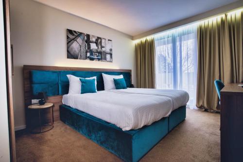 a bedroom with a large bed with a blue headboard at Hotel Nais Nis Autoput in Niš