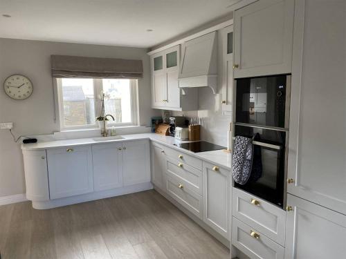a kitchen with white cabinets and a clock on the wall at 3 Bed in Doonbeg oc-ii15918 in Kilrush