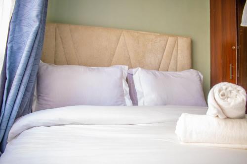 a bed with white sheets and pillows at Norlan Homes Kisumu in Kisumu