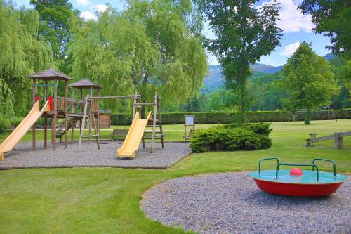 a playground with slides and a boat on the grass at Chambres les 4 saisons in Oust