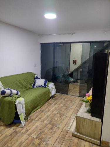 a living room with a green couch and a television at Casa para temporada próximo praça do canhão in São Pedro da Aldeia