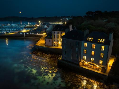 a night view of a building with lights in the water at ILE STAGADON - Appartement de luxe magnifique vue mer in Landéda
