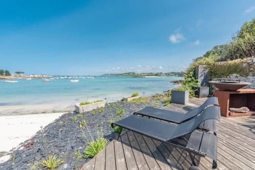 a bench sitting on a deck next to the beach at TY KOREJOU - splendide maison avec sauna les pieds dans l'eau in Plouguerneau