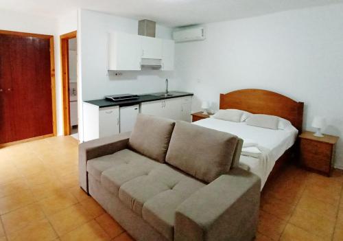 a bedroom with a bed and a couch and a kitchen at Faial Oceanfront Getaway AL in Horta