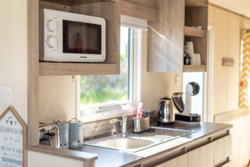 a kitchen with a sink and a microwave at Peaceful Spot at Seton Sands 3-Bed Caravan near Edinburgh in Port Seton