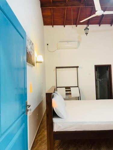 a bedroom with a bed and a blue door at Reef Inn by COOP in Hikkaduwa