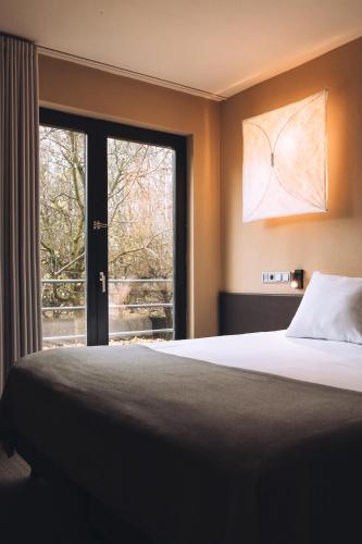 a bedroom with a bed and a large window at Vaeshartelt Maastricht - Free Parking in Maastricht