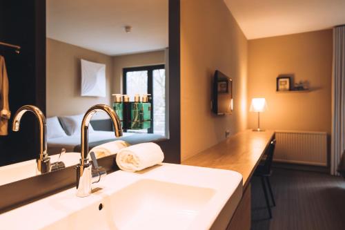 a bathroom with a sink and a bed in a room at Vaeshartelt Maastricht - Free Parking in Maastricht