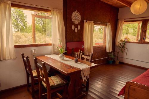 a dining room with a table and chairs and windows at Cabaña Viedma in Viedma