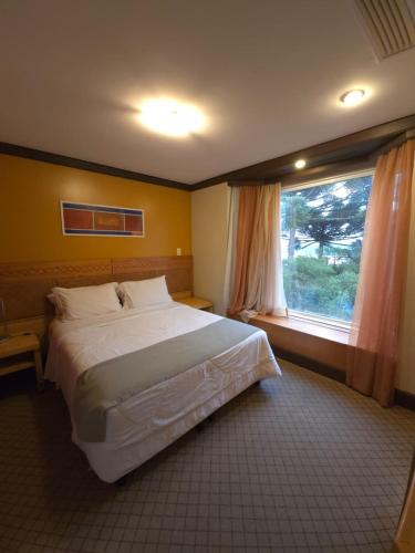 a bedroom with a large bed and a window at Flat Luxo 3010 com banheira Mountain Village Laje de Pedra Canela in Canela