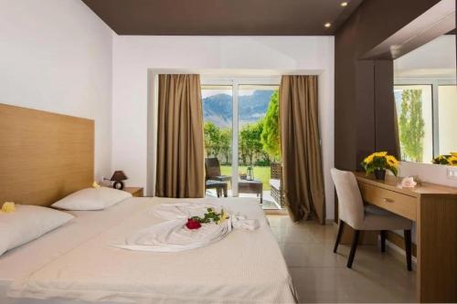 a hotel room with a bed and a desk with a flower on it at Anavadia Hotel By Anayia All Inclusive Resorts in Kolymbia