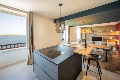 a kitchen with a island with a table and a view of the ocean at ILE WRACH - Duplex de luxe avec magnifique vue mer in Landéda