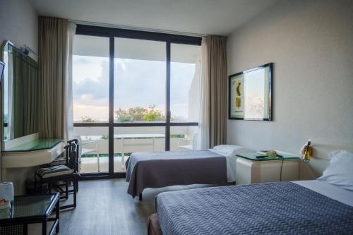 a hotel room with two beds and a large window at Grand Hotel Pianeta Maratea Resort in Maratea