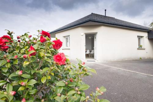 a white house with red roses in front of it at TY BIHAN - Charmante maison de plein-pied proche mer in Ploudalmézeau