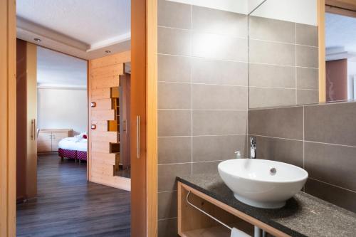 a bathroom with a sink and a room with a bed at Berg Hotel Latemar Spitze in Vigo di Fassa