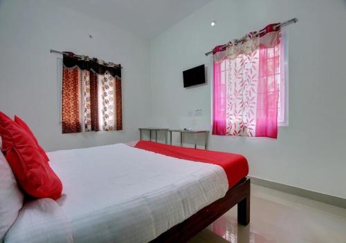 a bedroom with a bed with red pillows and windows at 3BHK - Bamboo Private Pool Villa Yercaud in Yercaud