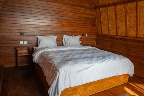 a bedroom with a large bed with wooden walls at Sea Cliff Eco Nusa Penida in Polilit