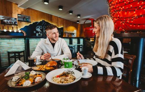a man and woman sitting at a table eating food at Hotel SKI in Belá