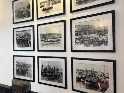 a group of framed photos of boats on a wall at The Swordfish Inn in Penzance