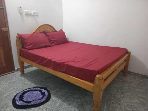 a bed in a room with a red blanket on it at BG Guest House Jaffna in Tirunelveli East