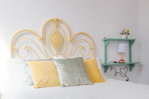 a white bed with a gold headboard and pillows at Aminta Home in Las Palmas de Gran Canaria