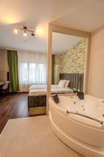 a hotel room with a tub and a bed at Hotel Mediteraneo Garni in Novi Sad