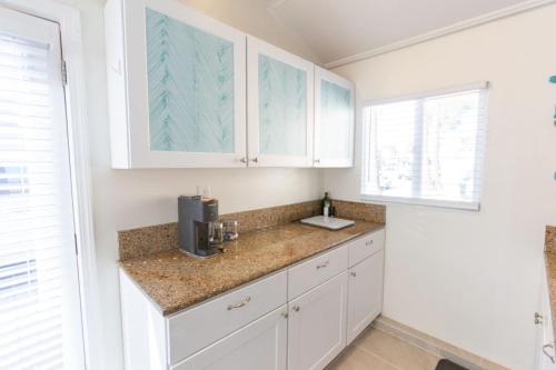 a kitchen with white cabinets and a sink at Beachside Bungalow steps from sand in San Diego