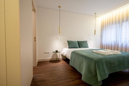 a bedroom with a bed with a green blanket at Music Apartment II in Bicas