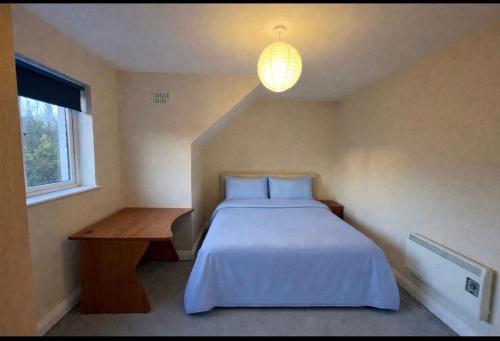 a bedroom with a bed and a table and a lamp at Large 3 bed Duplex Apartment - Rhebogue Limerick in Limerick