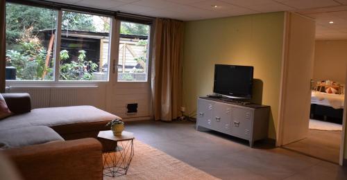 a living room with a couch and a flat screen tv at Nature and tranquility in Soest with Forest, Dunes and City in Soest