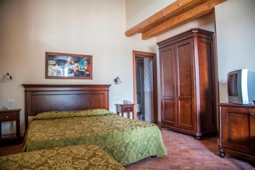 a bedroom with a bed and a dresser and a tv at Feudo Bauly in Palazzolo Acreide