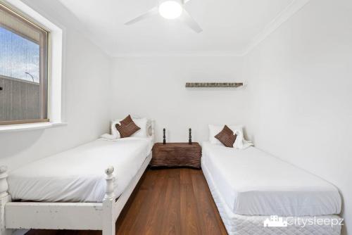 two beds in a white room with a window at Dean Park 2-Bed Unit in Deer Park