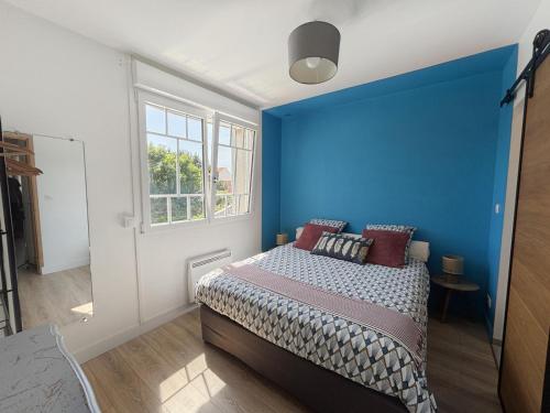 a blue bedroom with a bed and a window at L'Opale in Wimereux