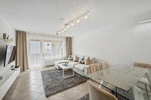 a living room with a white couch and a glass table at Ramoni Apartments - Naturglück in Enzklösterle