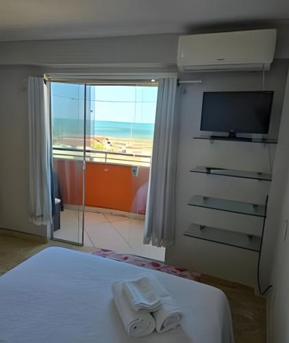 a bedroom with a bed and a tv and a window at Apartamento interino com vista mar in Natal