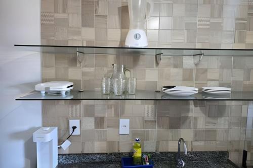 a kitchen with a shelf with dishes and a sink at Apartamento interino com vista mar in Natal