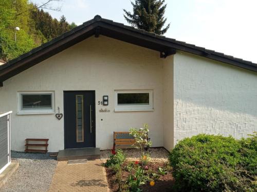 a white house with a black door and a bench at Holiday Home Stausee by Interhome in Biersdorf am See