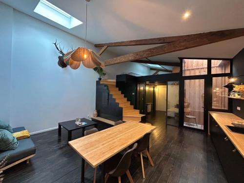 a living room with a wooden table and a staircase at Loft contemporain in Bordeaux