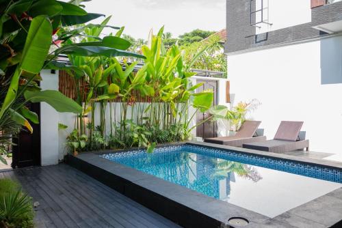 a swimming pool in the middle of a house with plants at The Aura Inn in Kerobokan