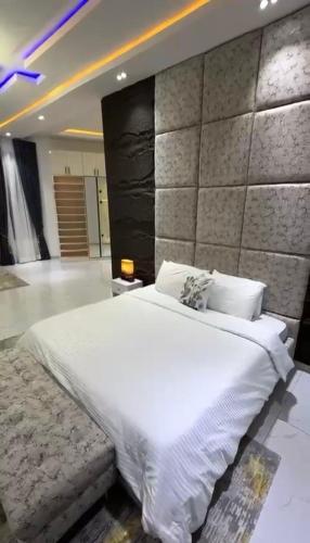 a bedroom with a white bed and a stone wall at 5bedroom duplex self compound in Lekki