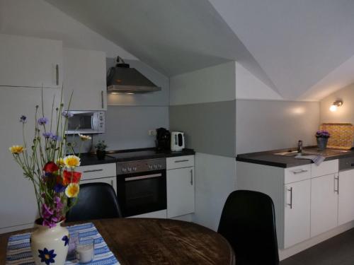 a kitchen with white cabinets and a table with a vase of flowers at Apartment Turmwohnung by Interhome in Kuchelmiß