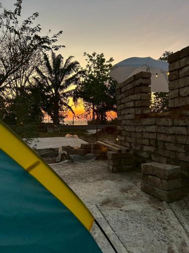 a sunset in a backyard with a brick wall at Jantawan Hostel in Ban Khlong Chet (2)