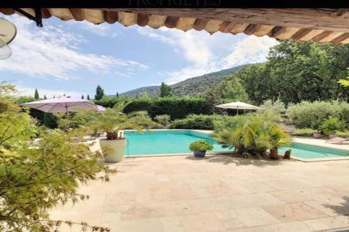 a swimming pool in a garden with mountains in the background at Gite Studio indépendant au cœur du Luberon in Maubec
