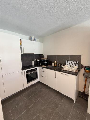a kitchen with white cabinets and a tile floor at Appartement Vue Montagne Vignoble Cosy Valais in Chamoson