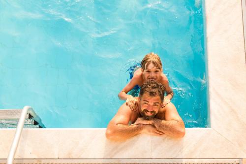 a man with a child on his shoulders in a swimming pool at Garner Hotel Glen Burnie BWI Airport Area by IHG in Glen Burnie