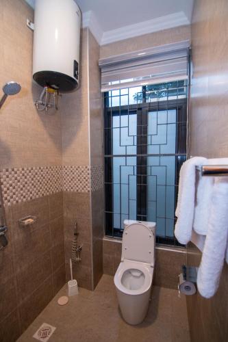 a bathroom with a toilet and a window and towels at Kilimont Hotel in Mabire