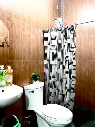 a bathroom with a toilet and a shower curtain at JRC Feel at Home in Puerto Princesa City