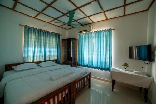 a bedroom with a large bed with blue curtains at Backwater Home in Kumarakom
