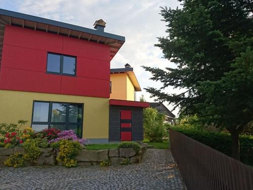 a red and yellow house with flowers in front of it at Holiday Home mit Wallbox by Interhome in Eibenstock