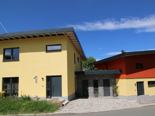 a large yellow house with a red building at Holiday Home mit Wallbox by Interhome in Eibenstock